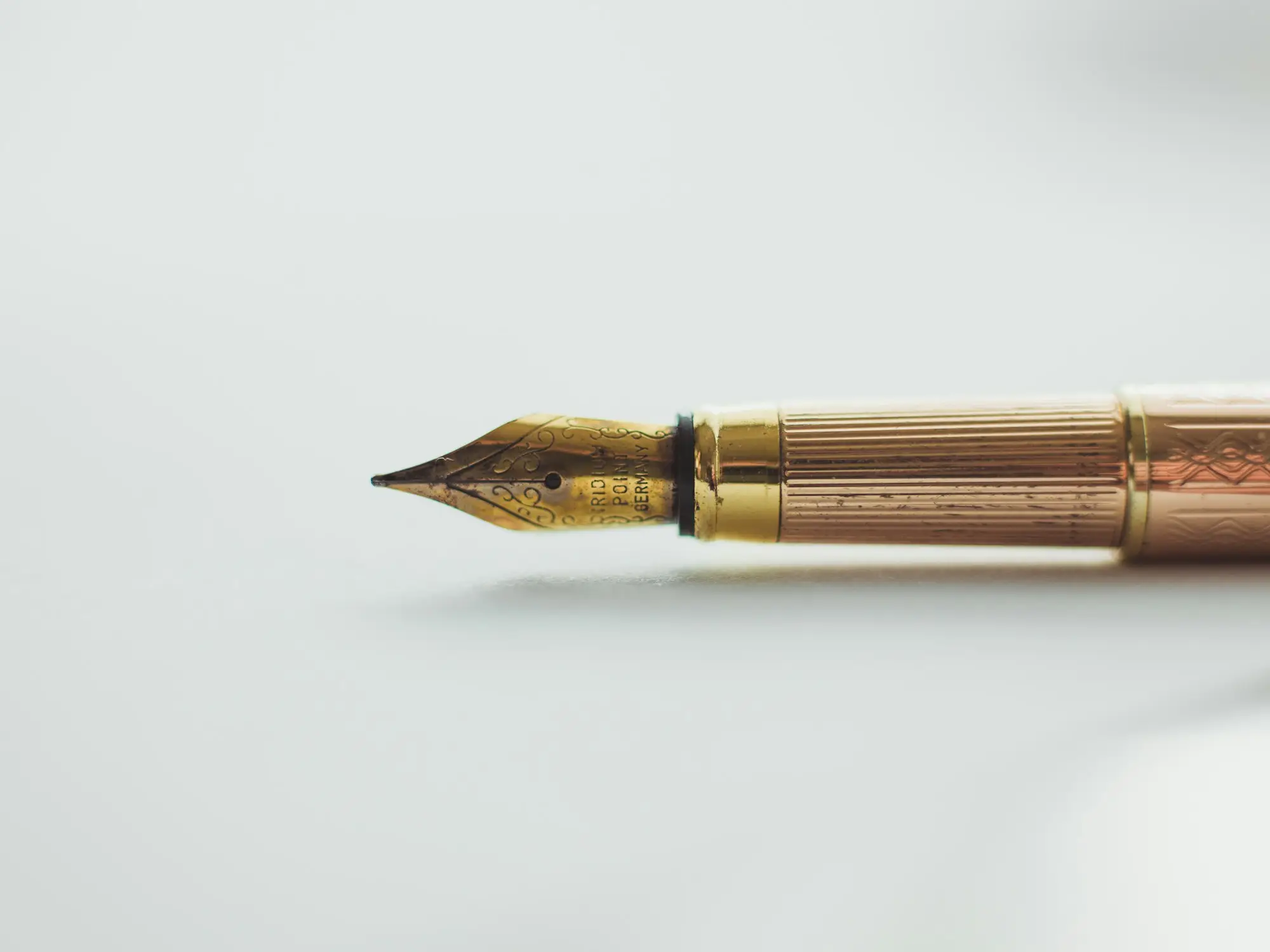 Gold fountain pen resting on a white desk, ready to sign a business loan mortgage with an all monies clause